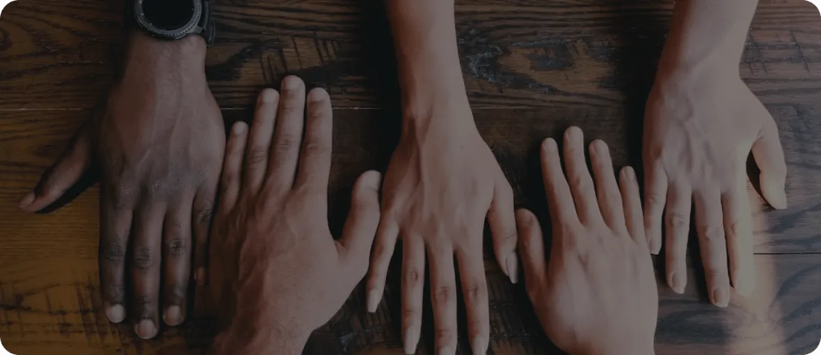 Five hands interchangeably placed opposite each other on a wooden table.