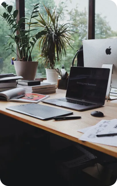 A top-down view of a desk with books, glasses, coffee and person's hands taking notes